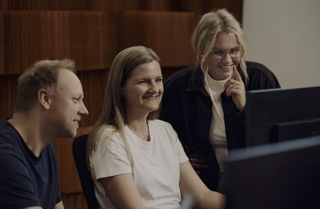 Tre personer ser på computerskærm sammen på kontor